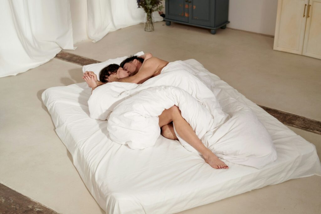 couple lying on bed covered with white blanket