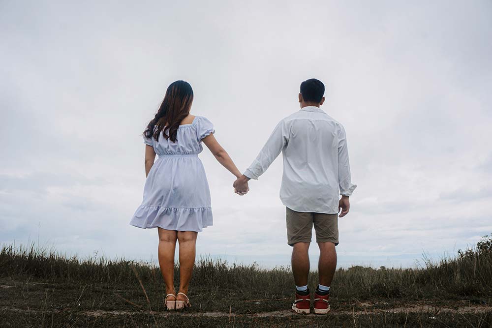 A Man and a Woman Holding Hands While Standing in a Field