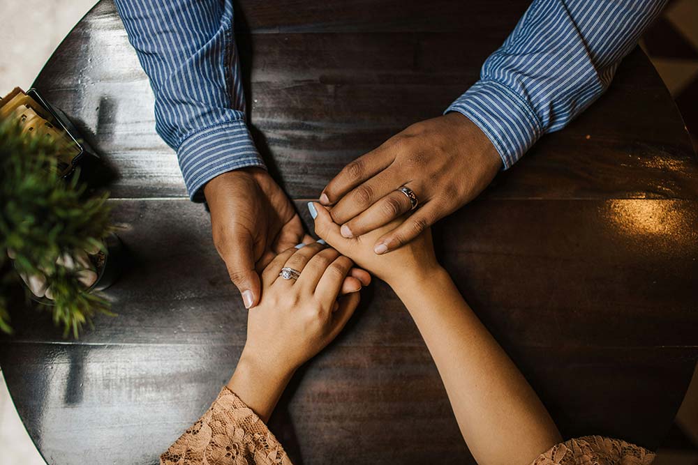 Hands Holding on a Brown Wooden Table