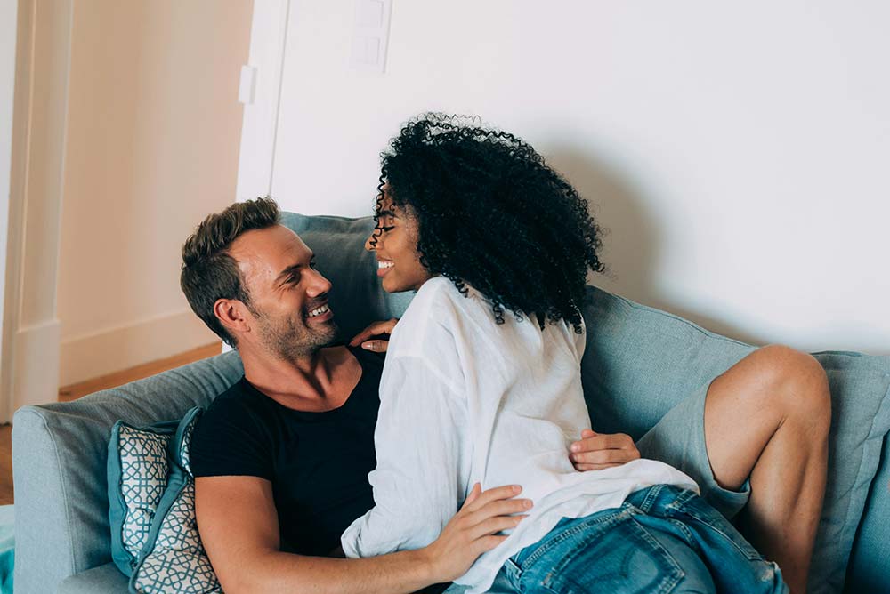 Happy young couple relaxing at home on the couch, having fun
