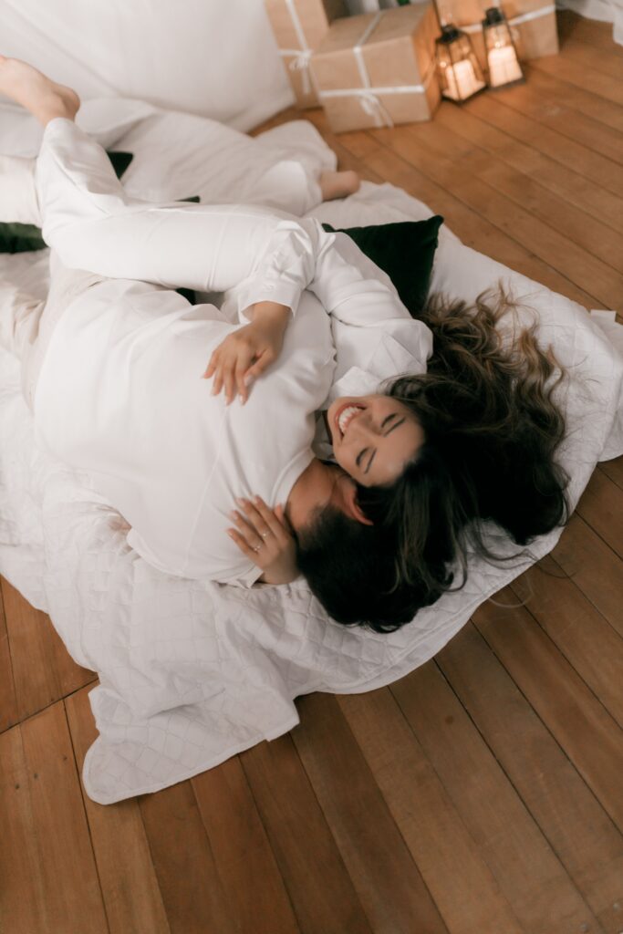 A happy young couple enjoying a cozy, affectionate morning together in a brightly lit modern bedroom.