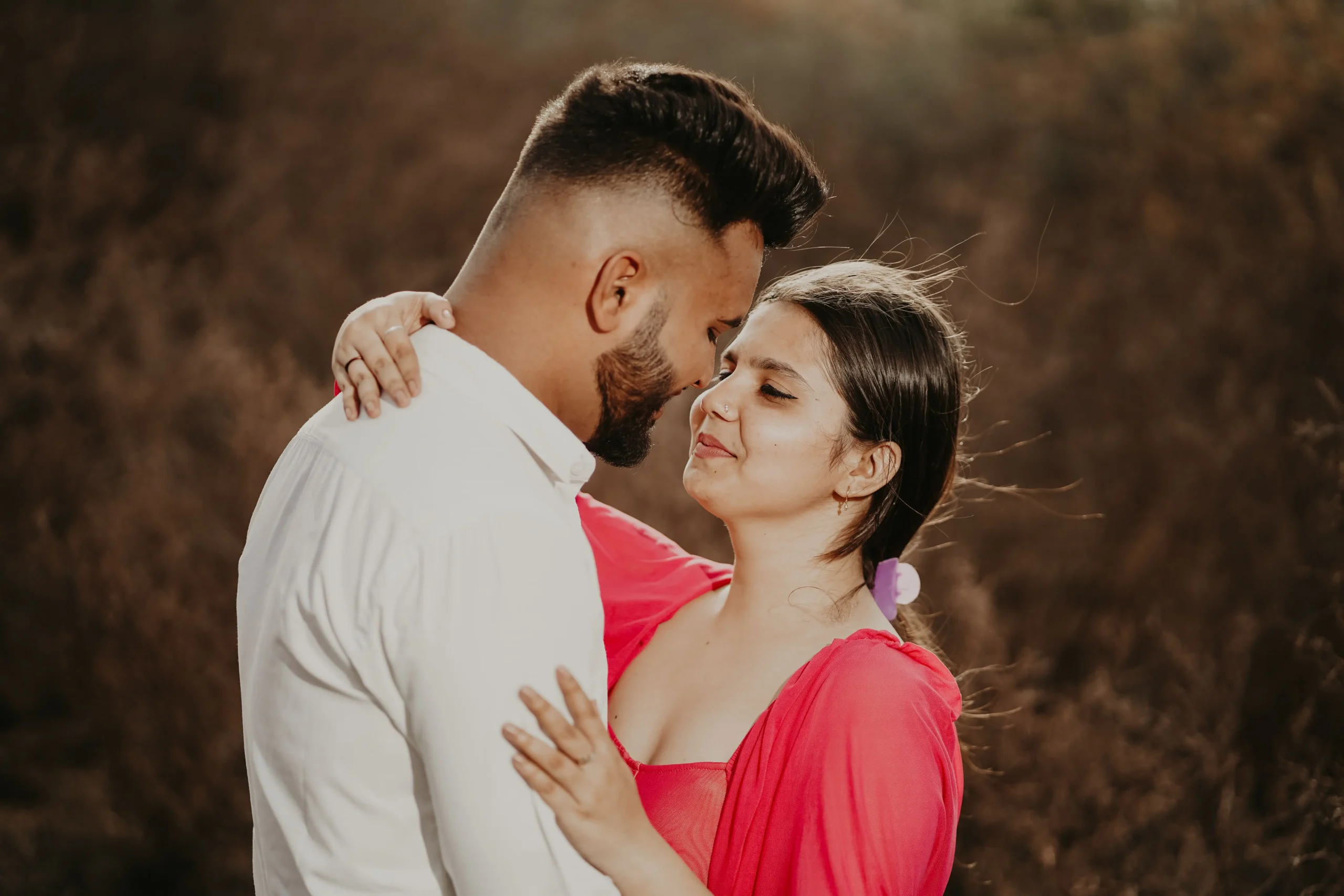 A man and woman looking at each other lovingly while hugging outside.
