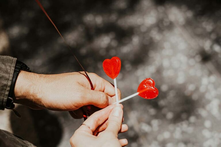two people holding a lollipop with two hearts on it
