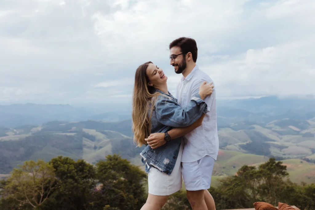 A couple hugging and laughing against an expansive mountain backdrop