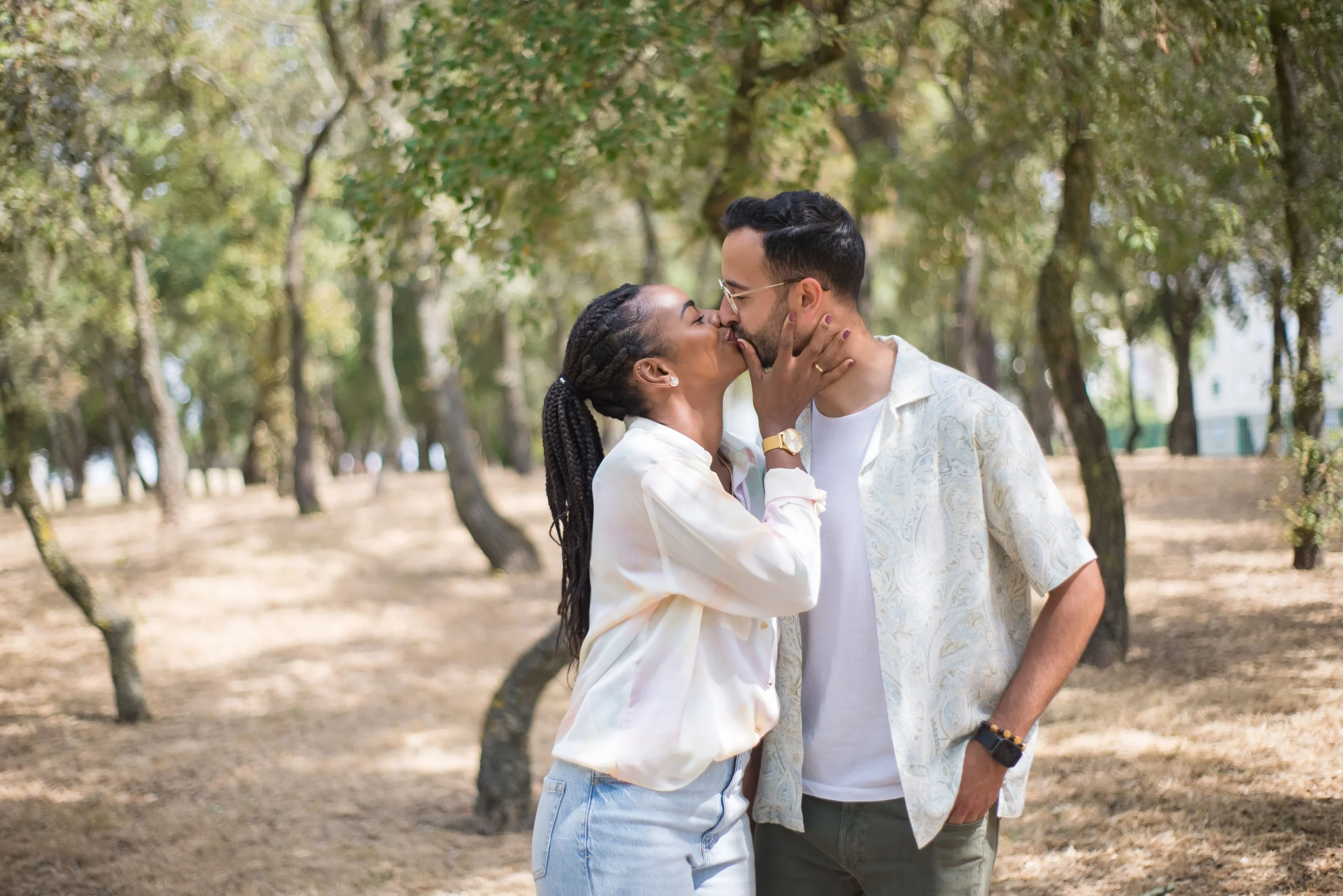 A couple kissing each other gently while standing among