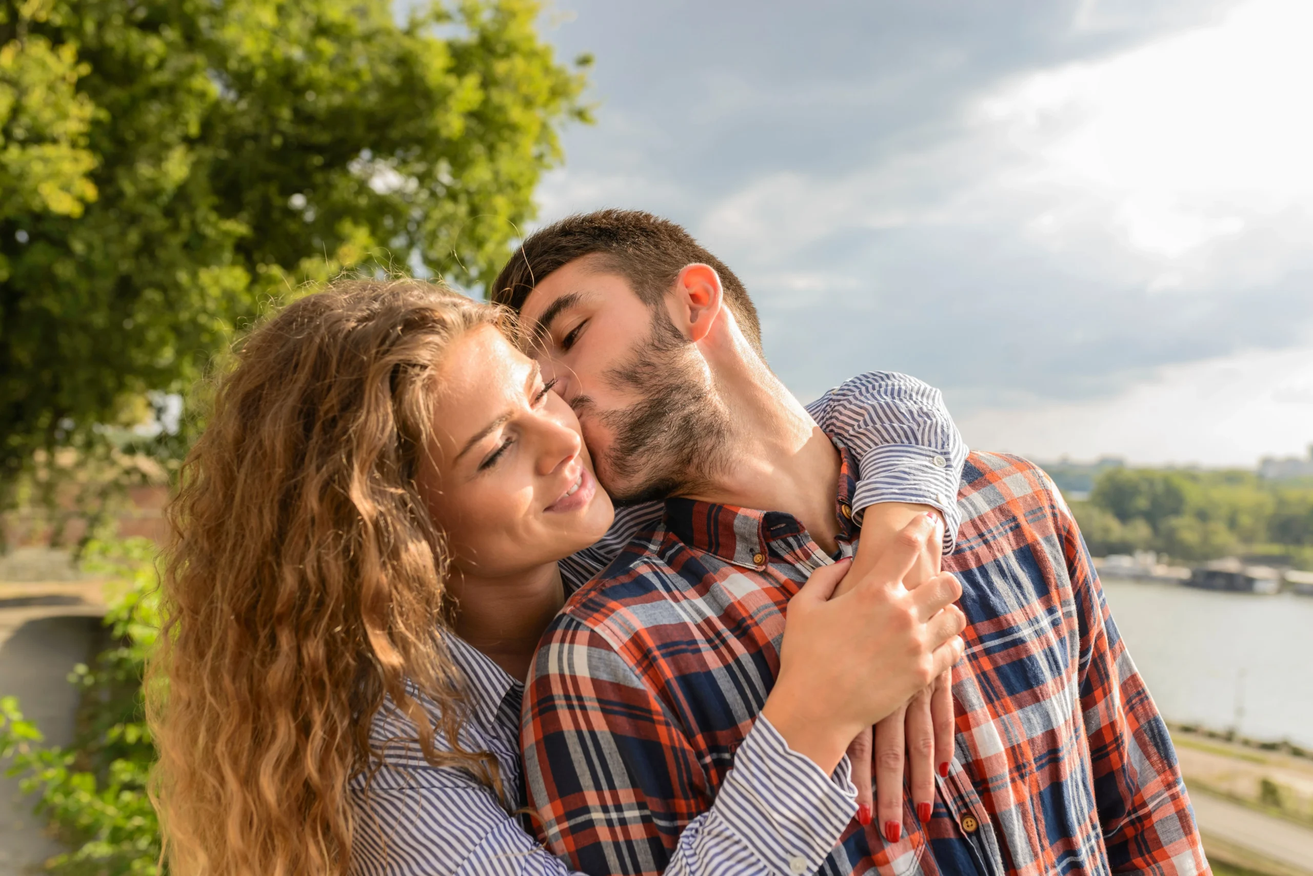 A man kissing a woman on the cheek as she embraces