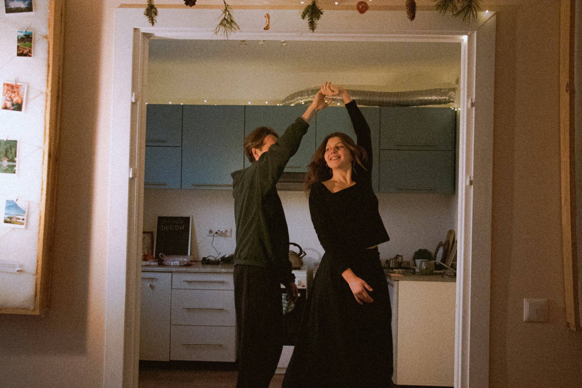 A couple dancing together in a kitchen doorway at home
