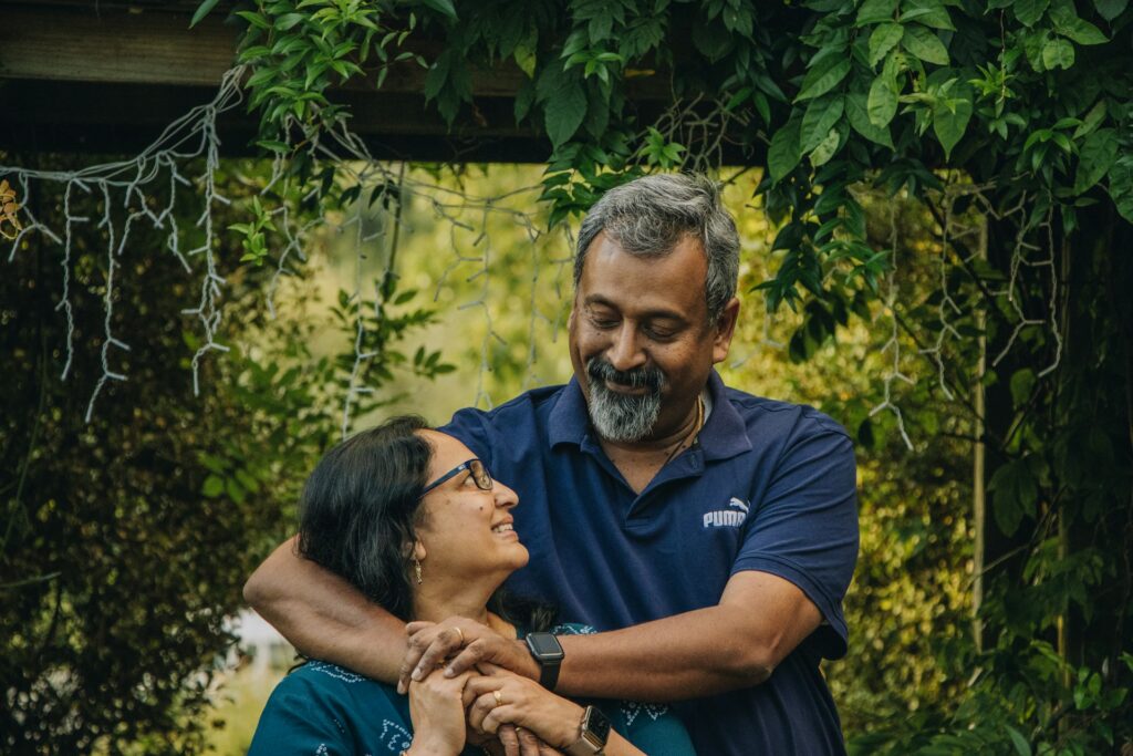 A couple holding each other close in a lush green garden setting