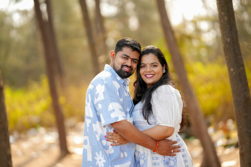 A man and a woman sharing a warm embrace in a sunlit forest surrounded by tall trees