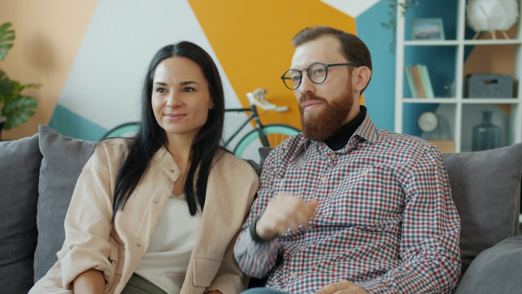 A smiling young couple relaxing and hugging on a couch in a bright apartment